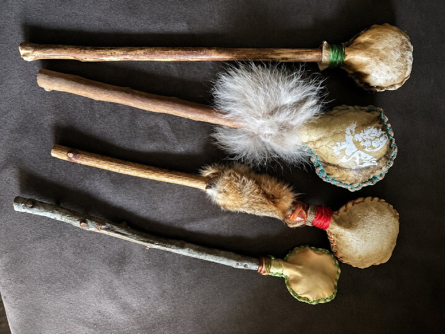 Four handmade ceremonial rattles of hide, wood, and fur